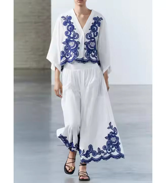 White outfit with blue embroidery on a plain background